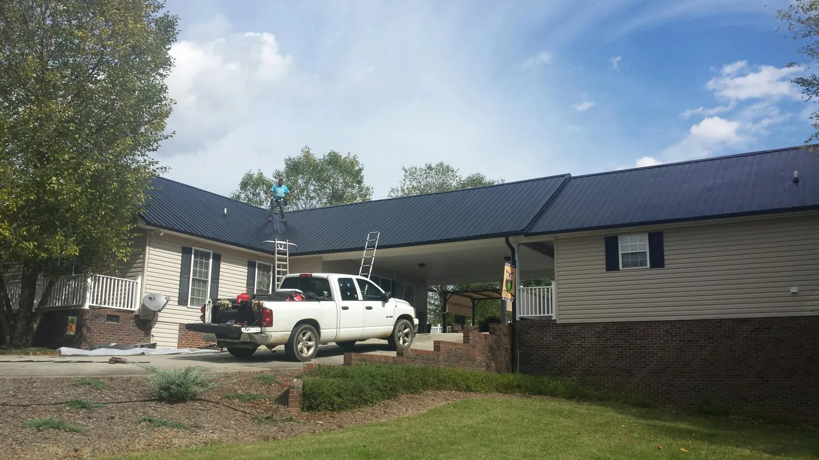 Black metal roof over a home and attached breezeway with ladders set in Holbrook